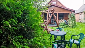 A wooden cabin with a porch, surrounded by lush greenery.
