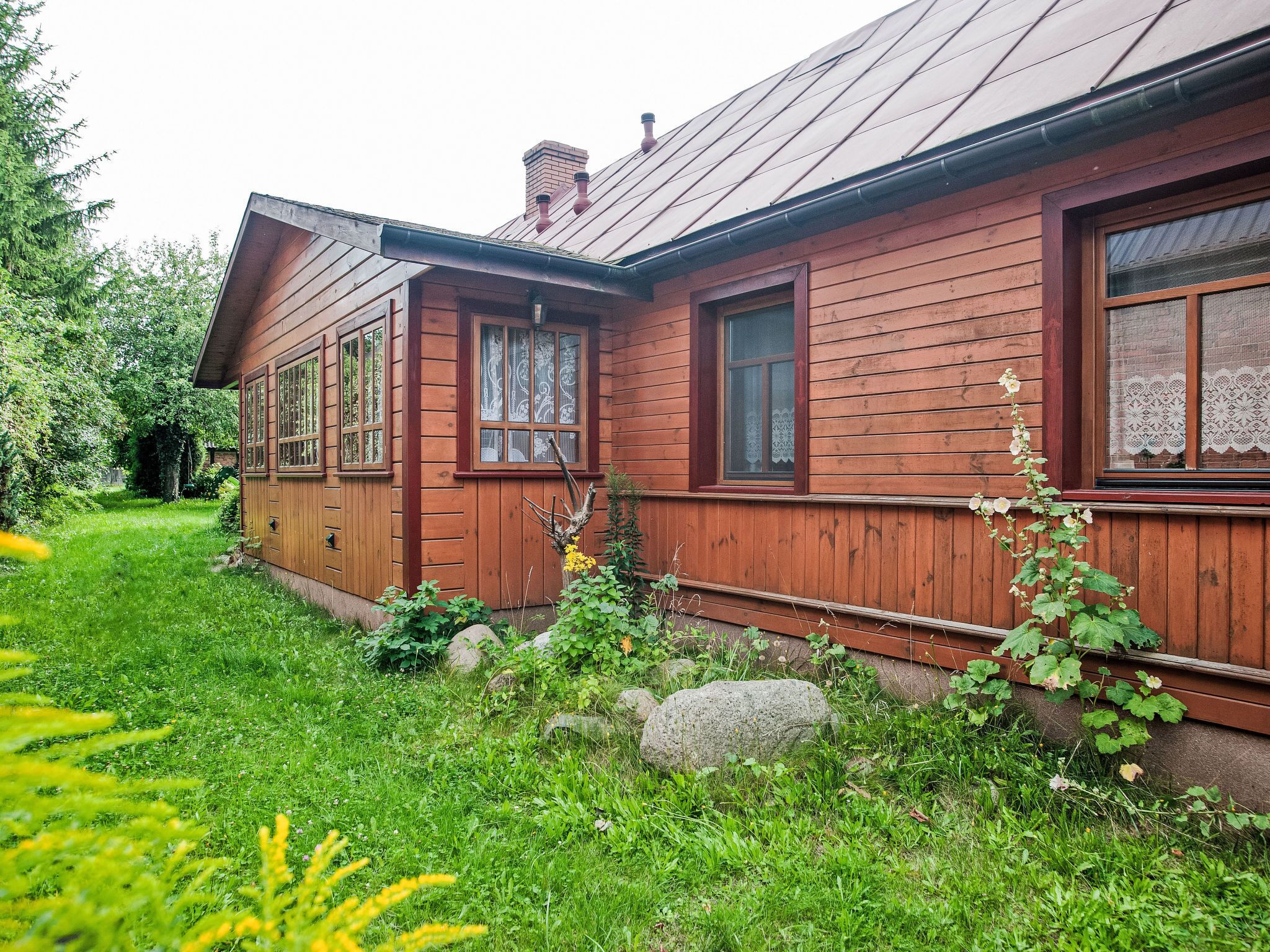 A wooden house with a sloped roof and a small garden in front.