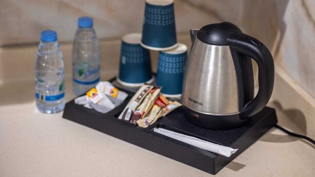 A tray with a kettle, water bottles, and disposable cups on a countertop. - Gardenia Park Al Zahraa Serviced Apartments (Economy) (Jeddah)