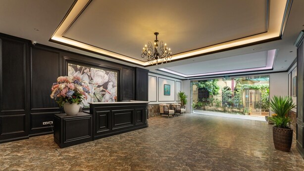 Eine geräumige Lobby mit Marmorboden, einem Empfangstresen, einer Kristallleuchtre und Blick ins Freie.