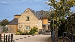 A stone building with a sloped roof, a gated entrance, and a small garden area.