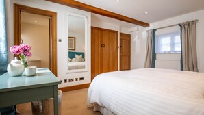 A bedroom with a bed, a bedside table with a teapot and cup, a mirror, and wooden wardrobes.