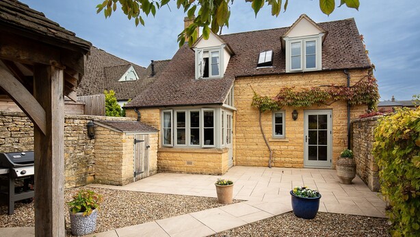 A stone house with a tiled patio, a wooden deck, and a barbecue grill. - Old Orchard Cottage - Pet friendly, Moreton-in-Marsh (Moreton-in-Marsh)