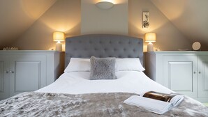 A bedroom with a tufted headboard, white bedding, a fluffy throw, and two bedside lamps. - Old Orchard Cottage - Pet friendly, Moreton-in-Marsh (Moreton-in-Marsh)