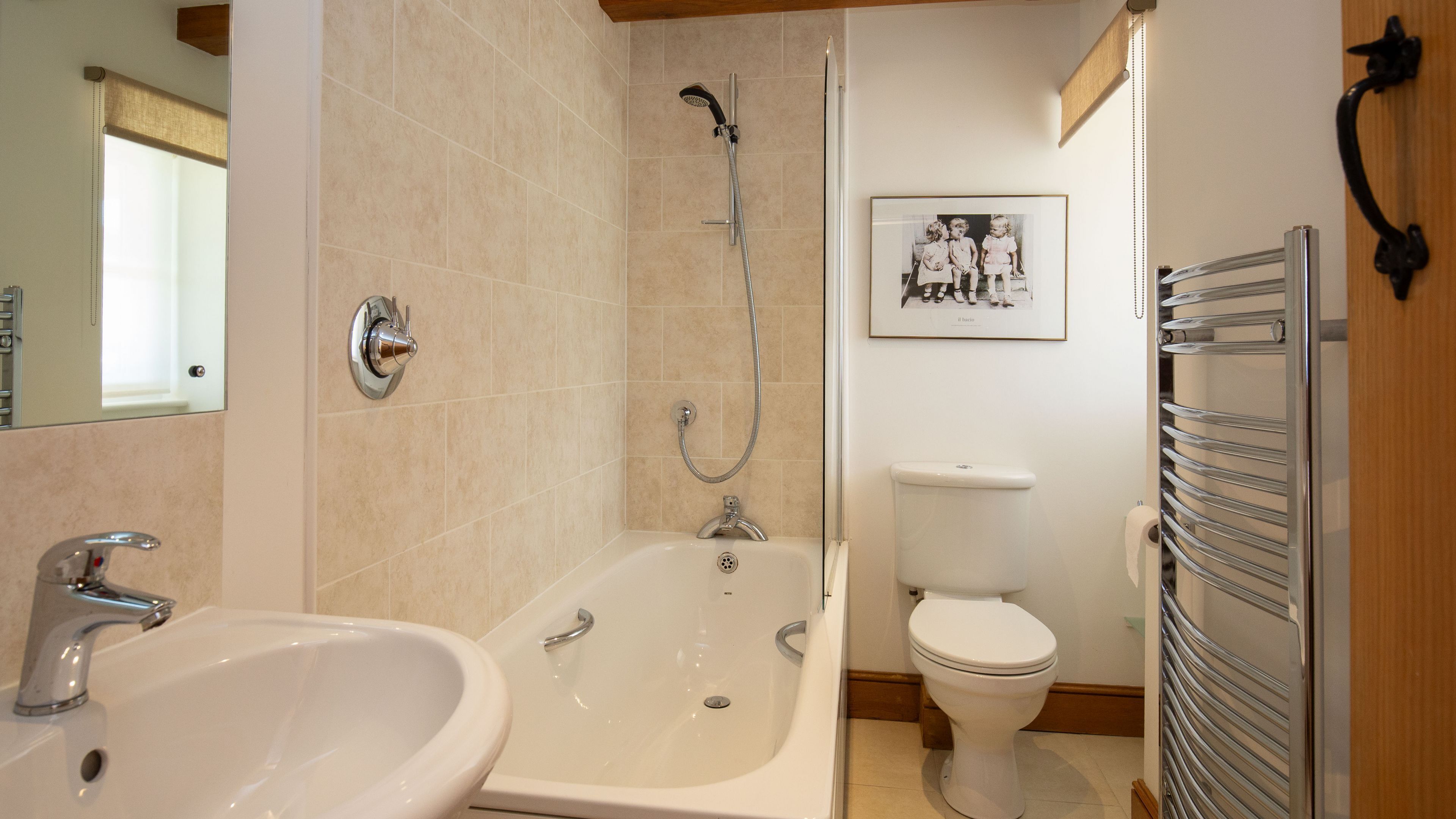 Un baño con bañera, lavamanos, inodoro y una fotografía en un marco en la pared.