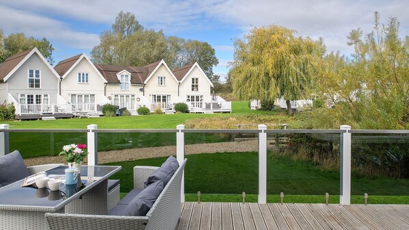 Een woonwijk met meerdere huizen, een gazon en een houten terras met buitenmeubilair.