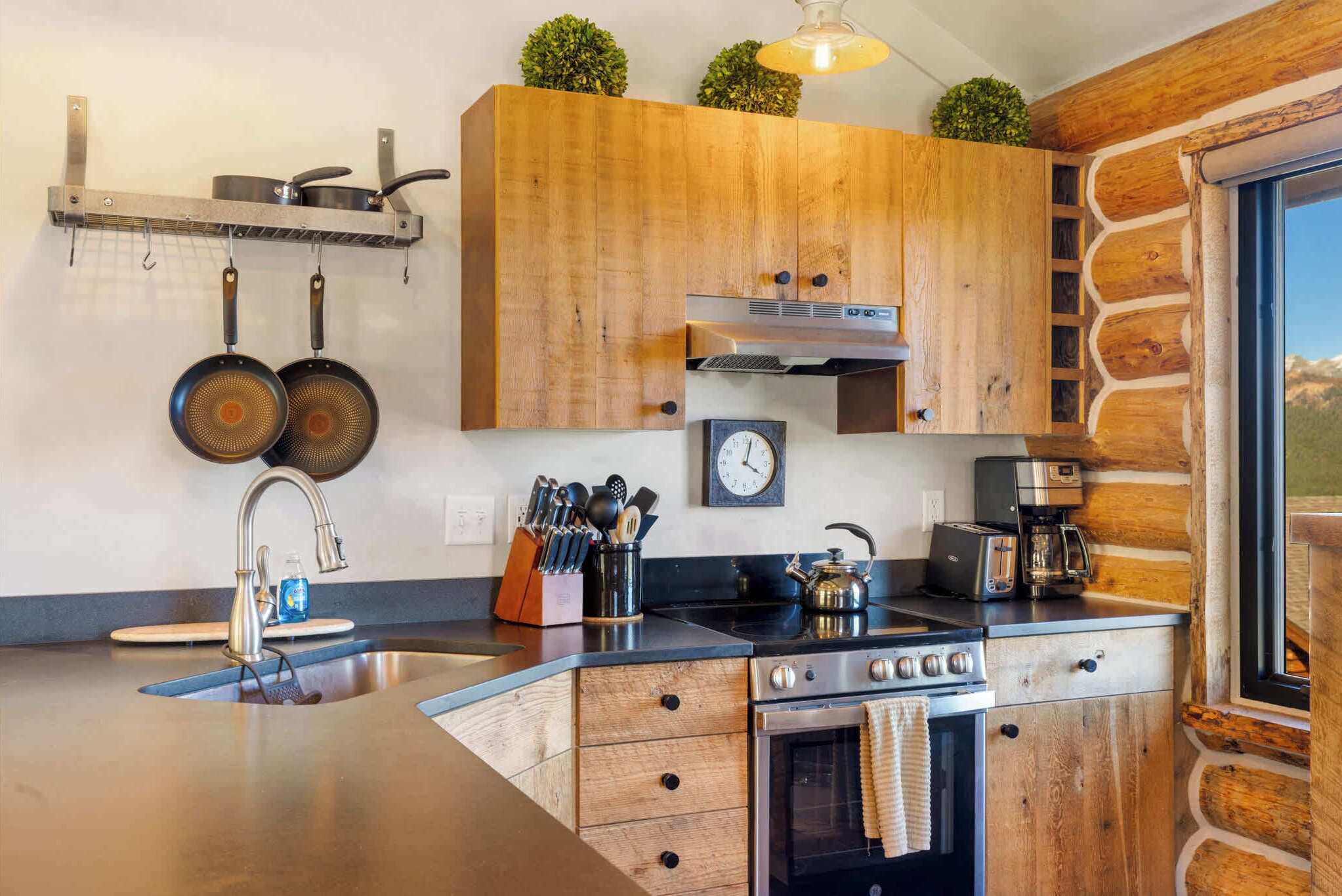 A kitchen with wooden cabinets, a stainless steel sink, a stove, and a coffee maker.