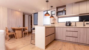 Eine moderne Küche mit Holzschränken, einer eingebauten Mikrowelle und Pendelleuchten.