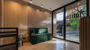 Een modern interieur met een groene, bekleden bank, een wand van houten latten en een glazen deur die naar buiten leidt.