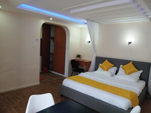 Quarto de hotel com cama, escrivaninha e cadeira.
