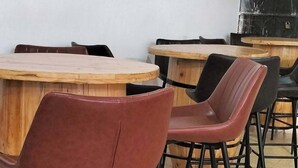 Un espace repas avec des tables en bois et des chaises en métal noir.