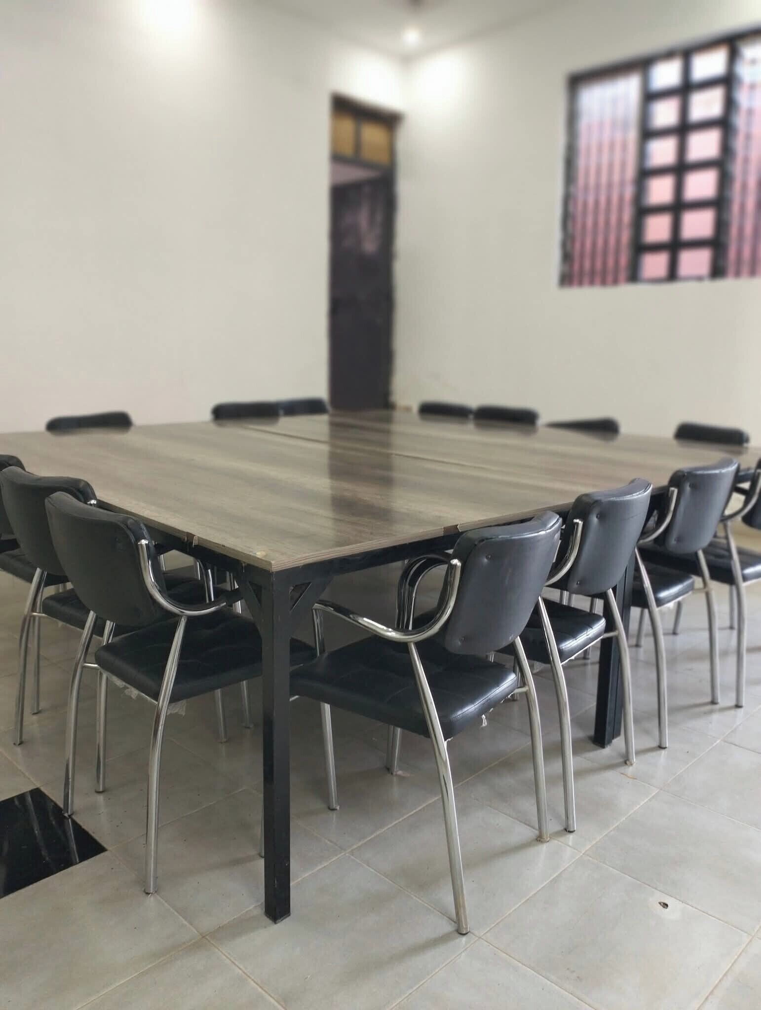 A conference room with a long table and black chairs.