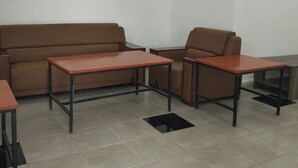 Une pièce avec un canapé marron, deux tables rouges et un tapis noir.