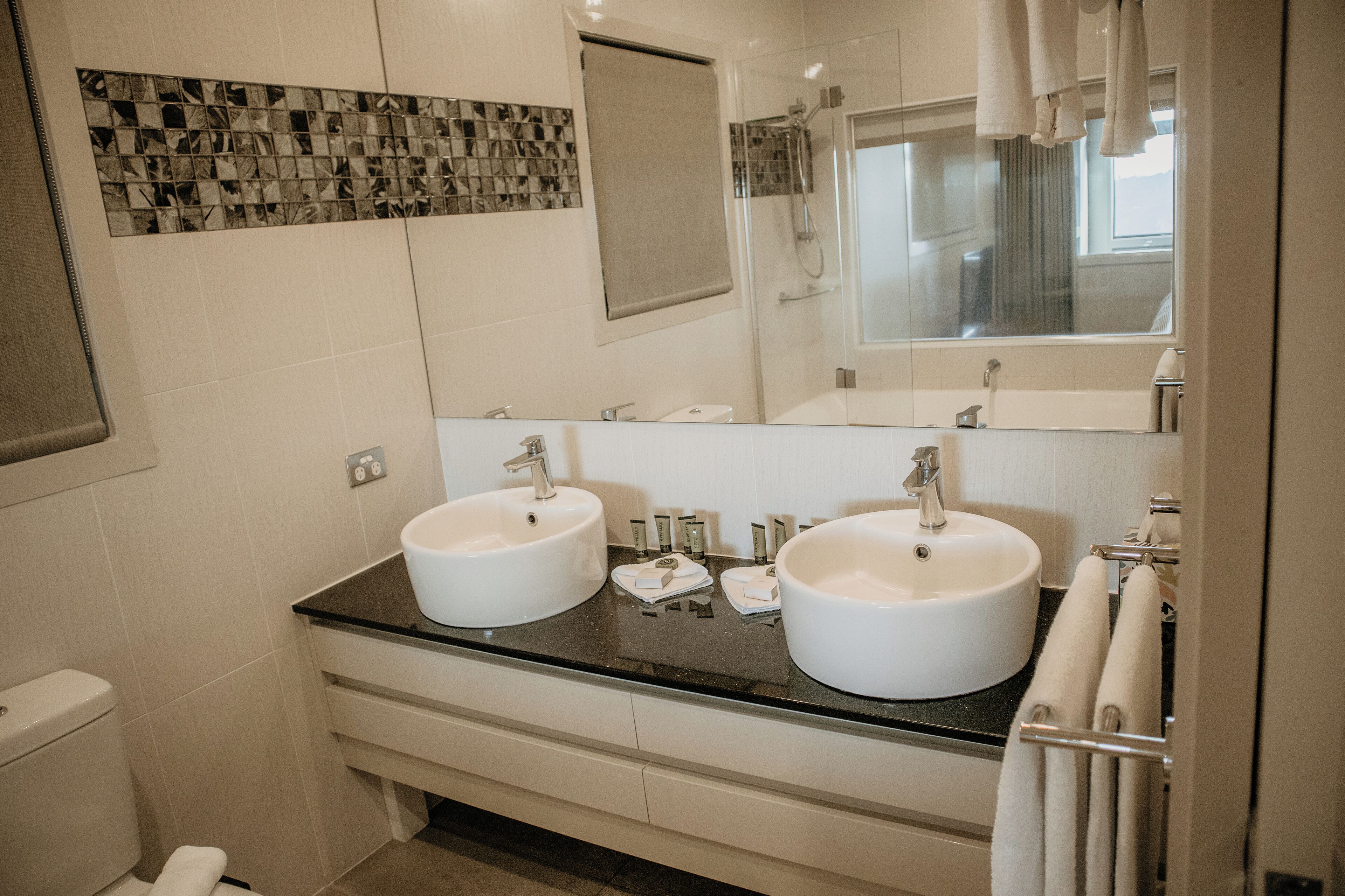 A bathroom with two sinks, a shower, and a mirror.
