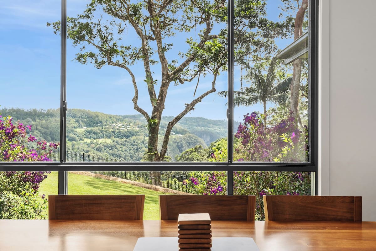 Un espace repas offrant une vue sur un paysage luxuriant grâce à de grandes fenêtres.