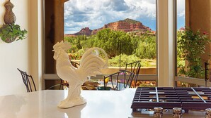 A dining area with a view of red rock formations, a white rooster sculpture, and a piano. - Bell Rock Haven // 3bd 3.5ba // Amazing Views (Sedona)