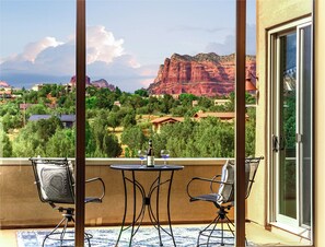 Ein Balkon mit zwei Stühlen und einem Tisch, mit Blick auf eine malerische Landschaft aus roten Felsformationen und Grünflächen.