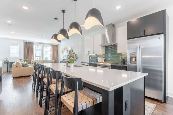 A modern kitchen with a central island, stainless steel appliances, and pendant lighting.