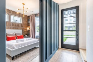 A modern hotel room with a large bed, a desk, and a view of the outside.