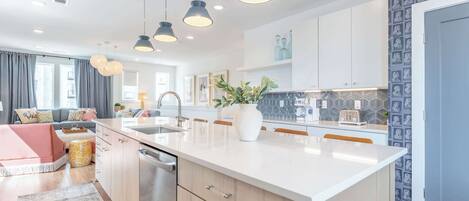 Una cucina moderna con una grande isola, luci a sospensione e un piano di lavoro con motivo geometrico.