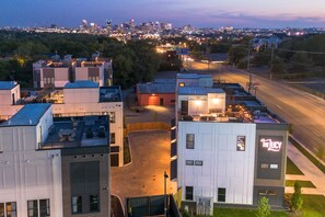 A multi-story building with a rooftop patio area, a sign reading "The Jucy," and a parking lot in the foreground.