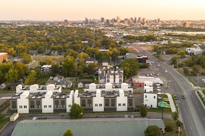 A multi-story building with a flat roof, surrounded by trees and a road.