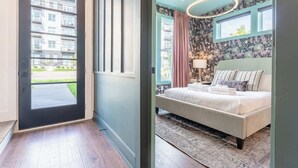 A bedroom with a bed, a window, a curtain, and a wall with floral wallpaper. - Two Nashville homes with hot tub, rooftop fire pit & grill, sleeps 24 (Nashville)