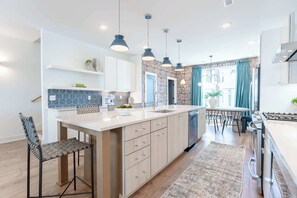 A modern kitchen with a central island, pendant lights, and a dining area with a table and chairs.