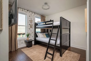 A bunk bed room with a TV, a small table, a plant, and a window with curtains. - Two rooftop homes with hot tub & fire pit, sleeps 20 near Broadway, Nashville (Nashville)