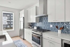A modern kitchen with white cabinets, a stainless steel range, and a patterned backsplash. - Two rooftop homes with hot tub & fire pit, sleeps 20 near Broadway, Nashville (Nashville)