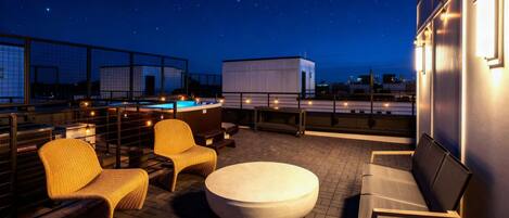 Terraza en la azotea con piscina, zona de estar y vistas al cielo nocturno.