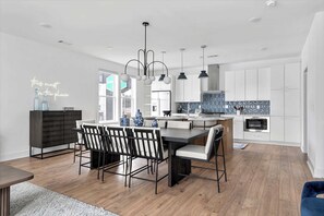 Une cuisine moderne avec des meubles blancs, un îlot central et des luminaires suspendus.