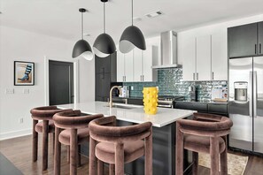 Une cuisine moderne dotée d’un îlot central, d’appareils électroménagers en acier inoxydable et d’un élément décoratif jaune original.