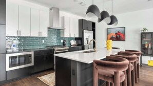 A modern kitchen with dark cabinetry, a central island, and pendant lighting.