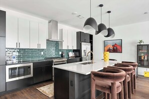 A modern kitchen with dark cabinetry, a central island, and pendant lighting.