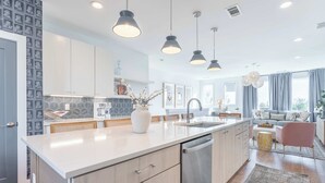 Una cucina moderna con isola centrale, elettrodomestici in acciaio inossidabile e illuminazione a sospensione.