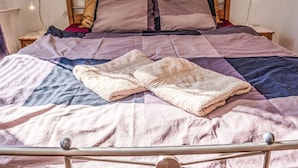 Un lit avec une couette, des oreillers et une couverture pliée.