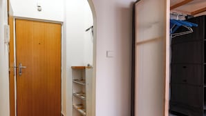 Un couloir avec une porte en bois, une étagère en métal et un meuble noir avec un cintre bleu.