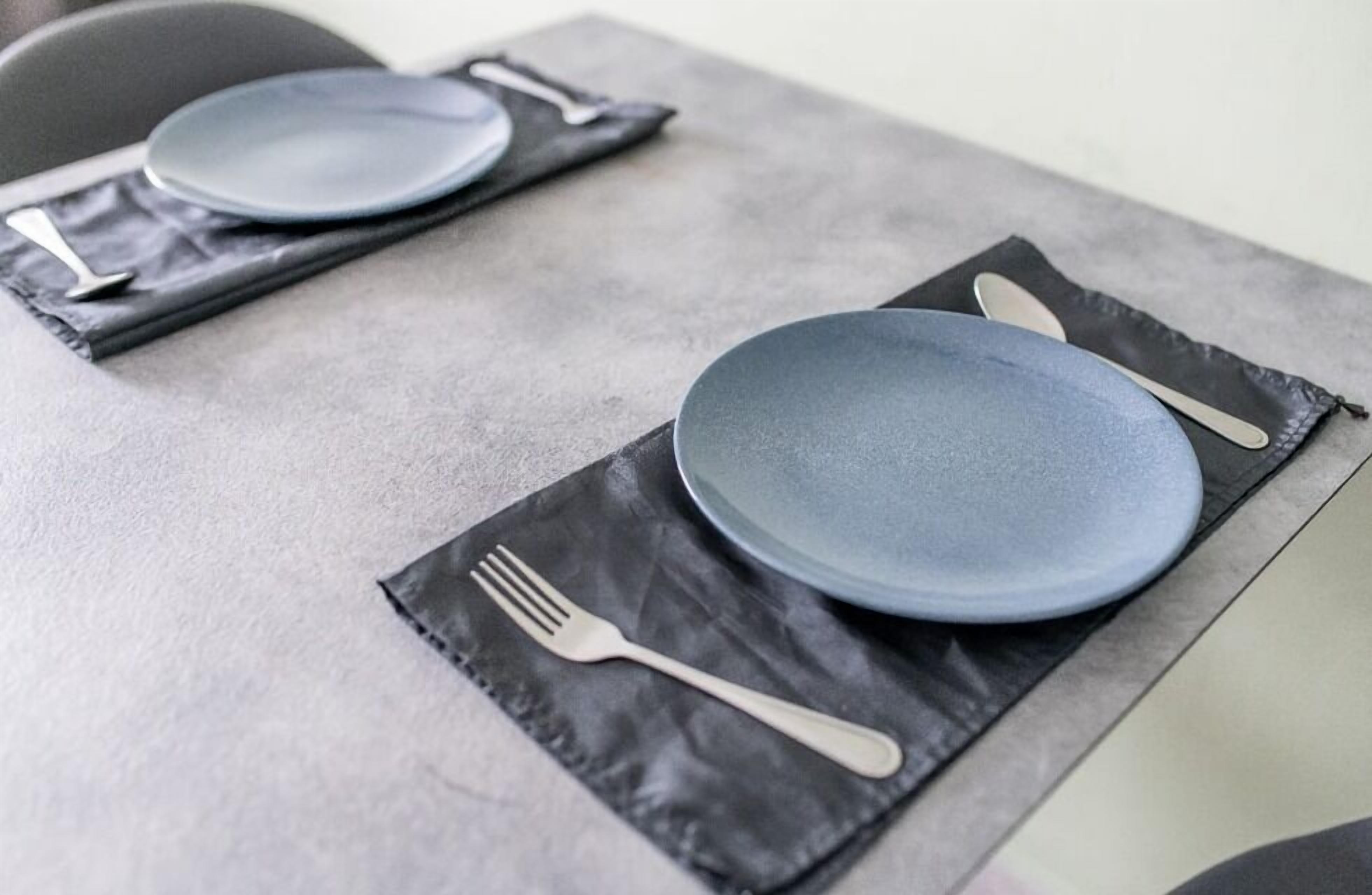 Una mesa con un plato, un tenedor y un cuchillo sobre un mantel negro.