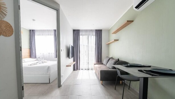 Una habitación de hotel moderna con cama, sofá, mesa de comedor y televisor.