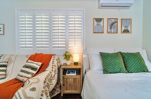 Une chambre à coucher avec un lit, une table de chevet, une lampe et des œuvres d’art murales.