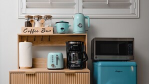 Eine Küchenzeile mit einer Kaffeebar, einem Toaster, einer Kaffeemaschine, einer Mikrowelle und einem Retro-Kühlschrank.