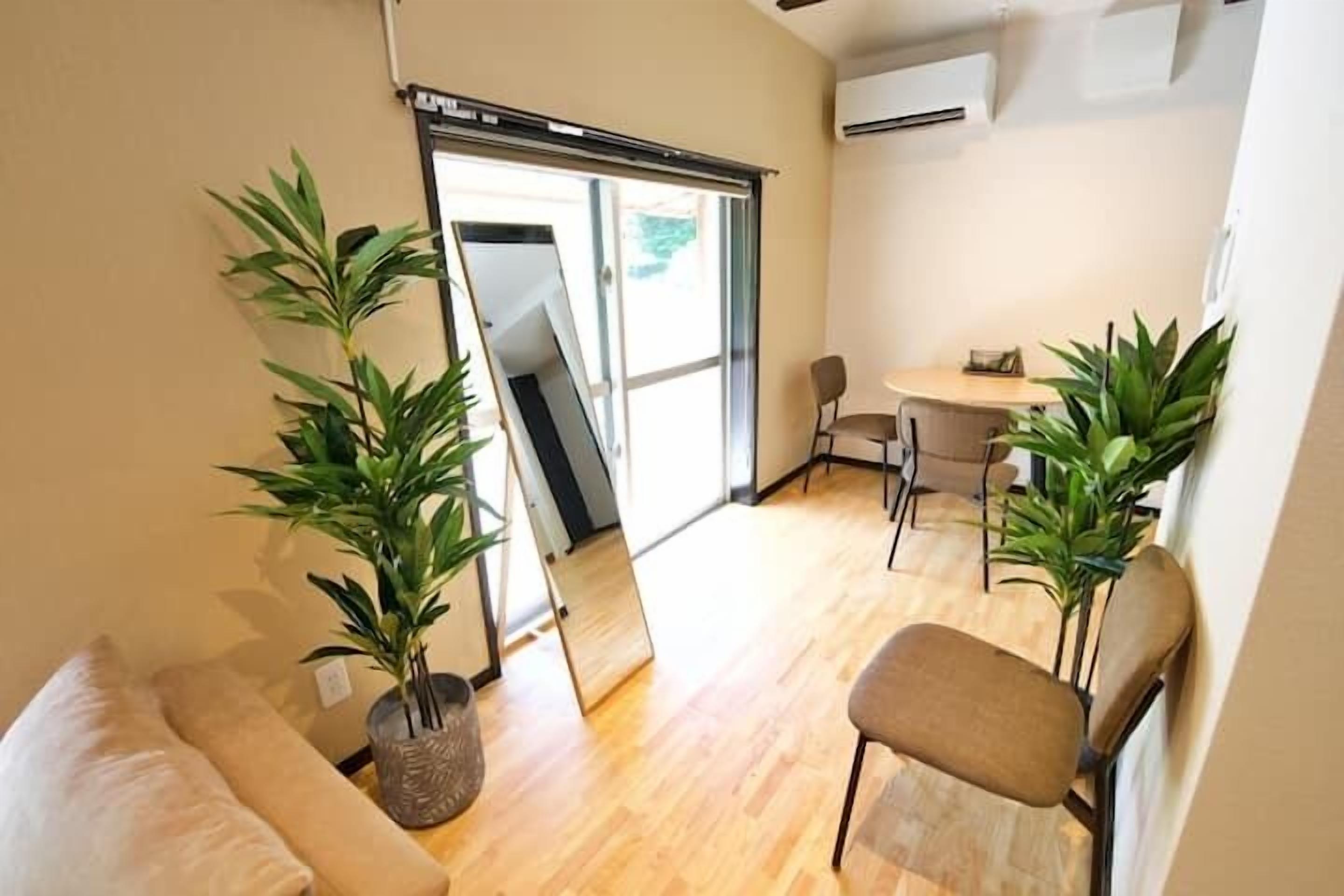 A modern living room with a sofa, two chairs, a small table, and two potted plants.