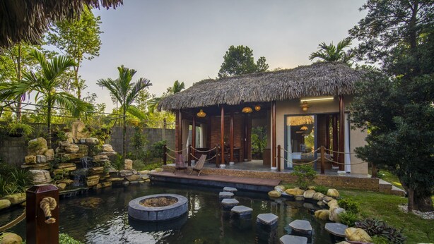 A thatched-roof building with a pool and stepping stones. - Lá Retreat (Da Nang)