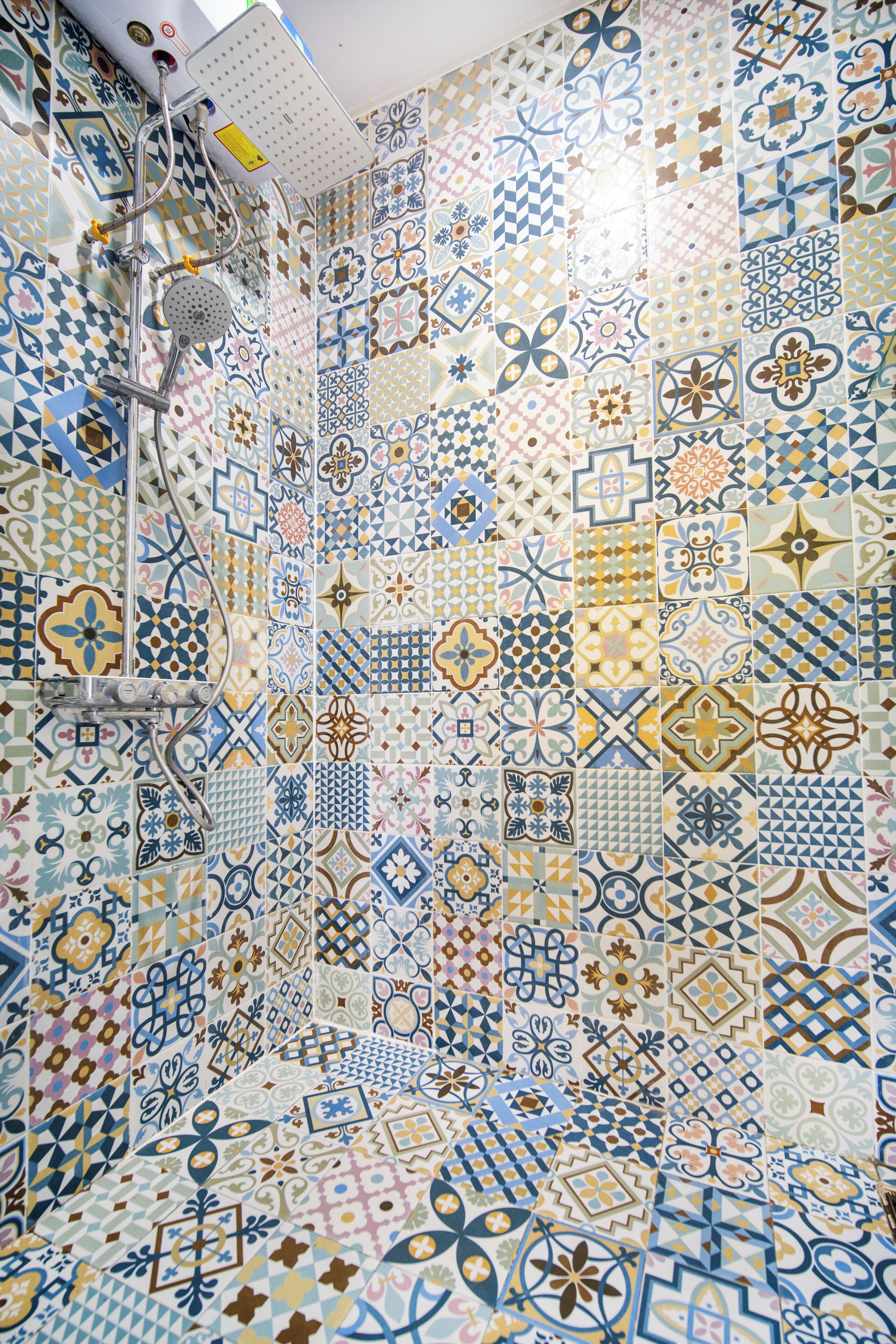 A bathroom with a shower area featuring a variety of patterned tiles.