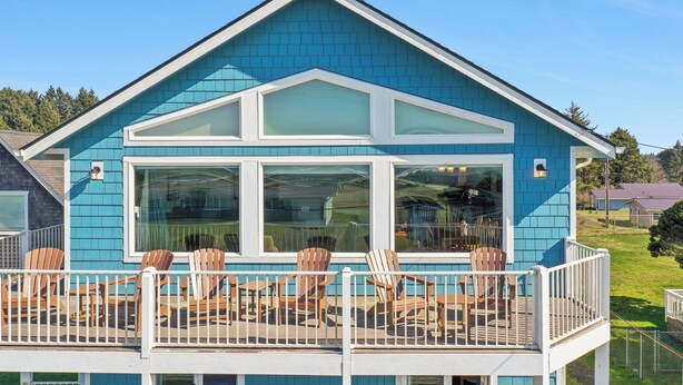 Une maison bleue avec un balcon et des chaises en bois.