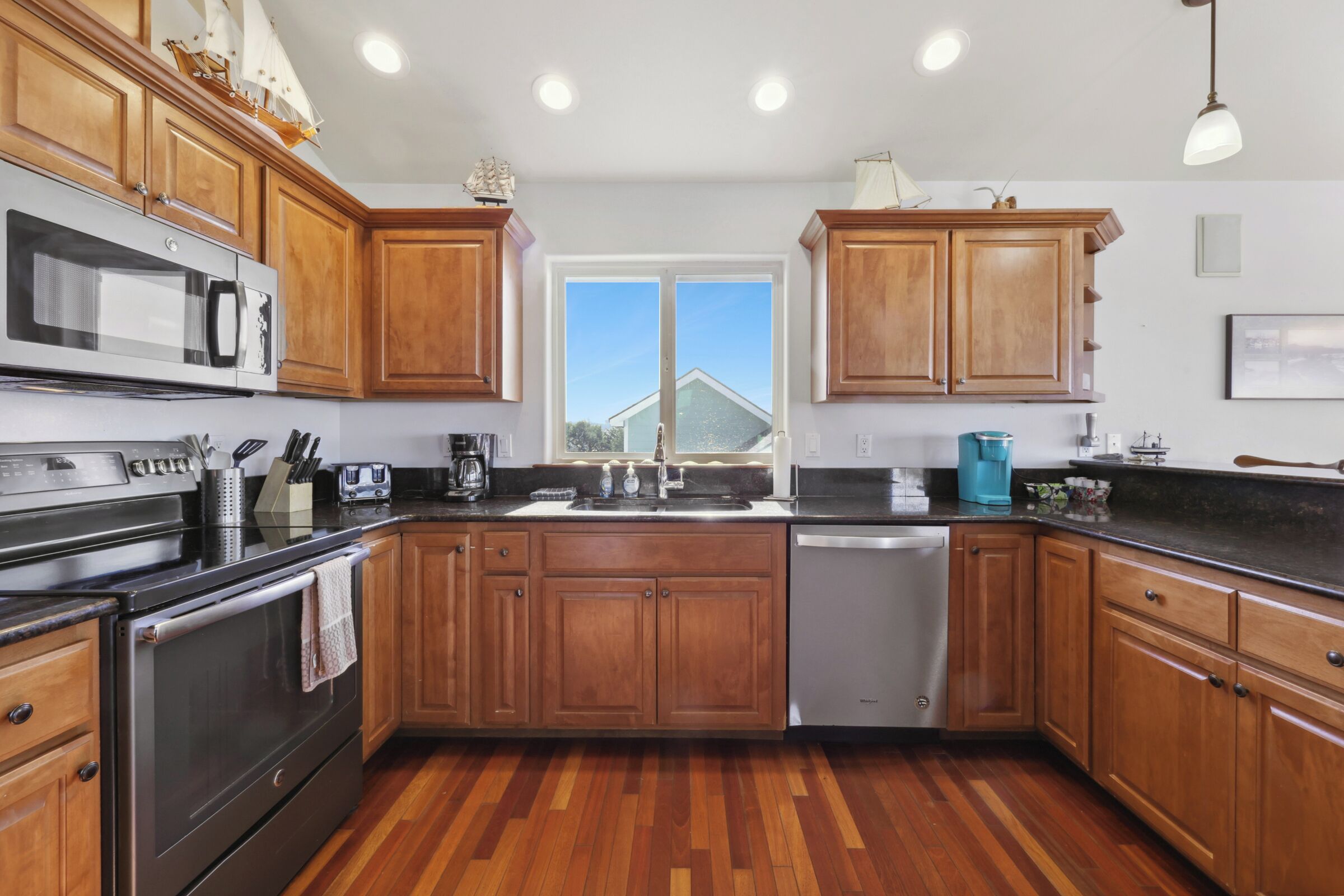 A kitchen with wooden cabinets, stainless steel appliances, and a large window.