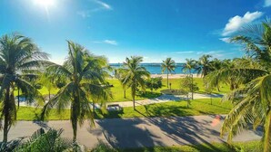 Un resort tropical con palmeras, cielo azul despejado y vista al océano.