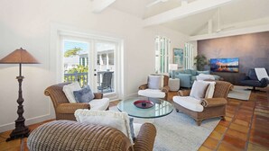 Amplia sala de estar con muebles de mimbre, una mesa de centro de vidrio y un televisor grande.