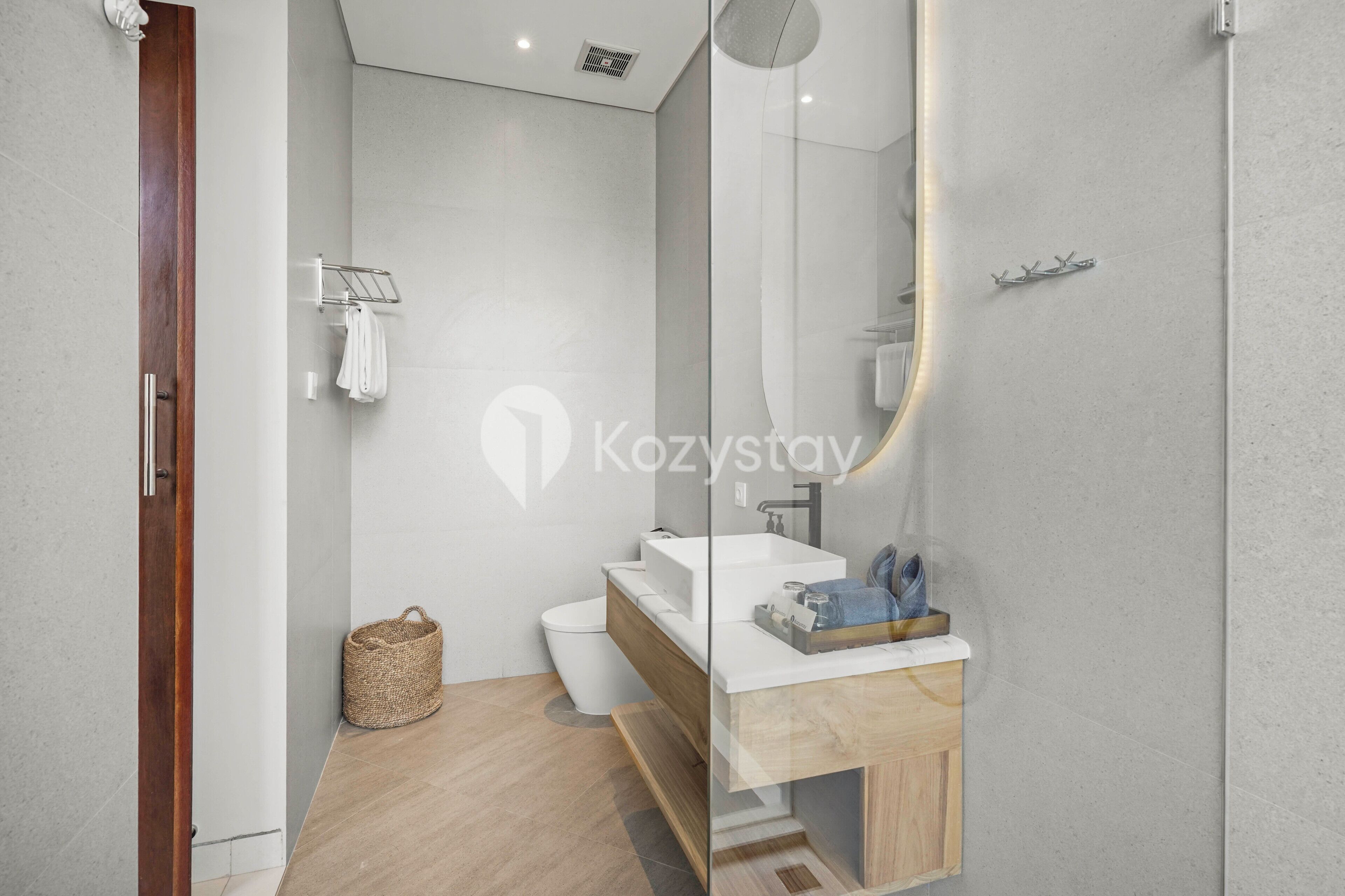 A modern bathroom with a wooden vanity, a white sink, and a large mirror.